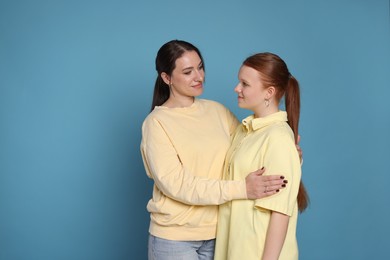 Photo of Portrait of beautiful mother with teenage daughter on light blue background