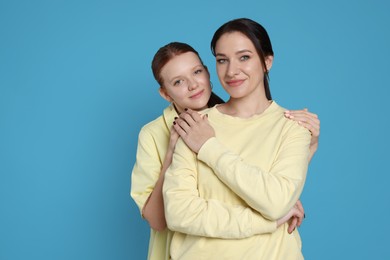 Photo of Portrait of beautiful mother with teenage daughter on light blue background