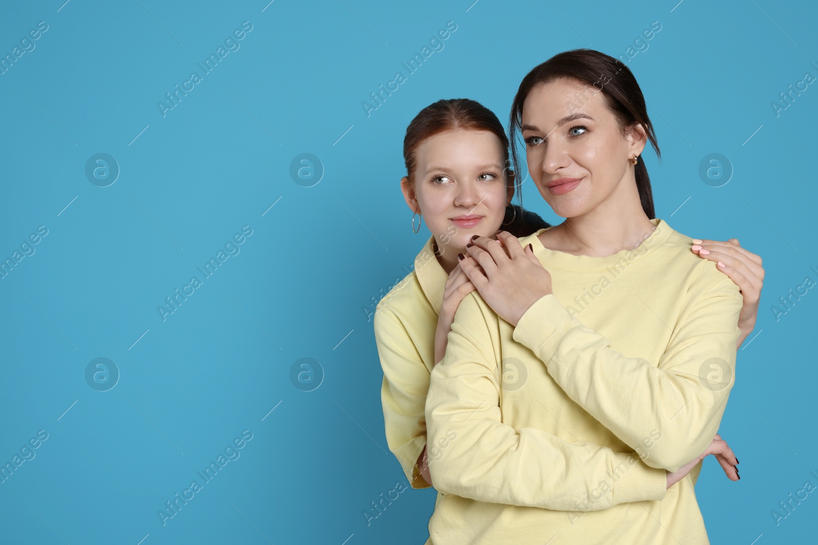 Photo of Portrait of beautiful mother with teenage daughter on light blue background, space for text