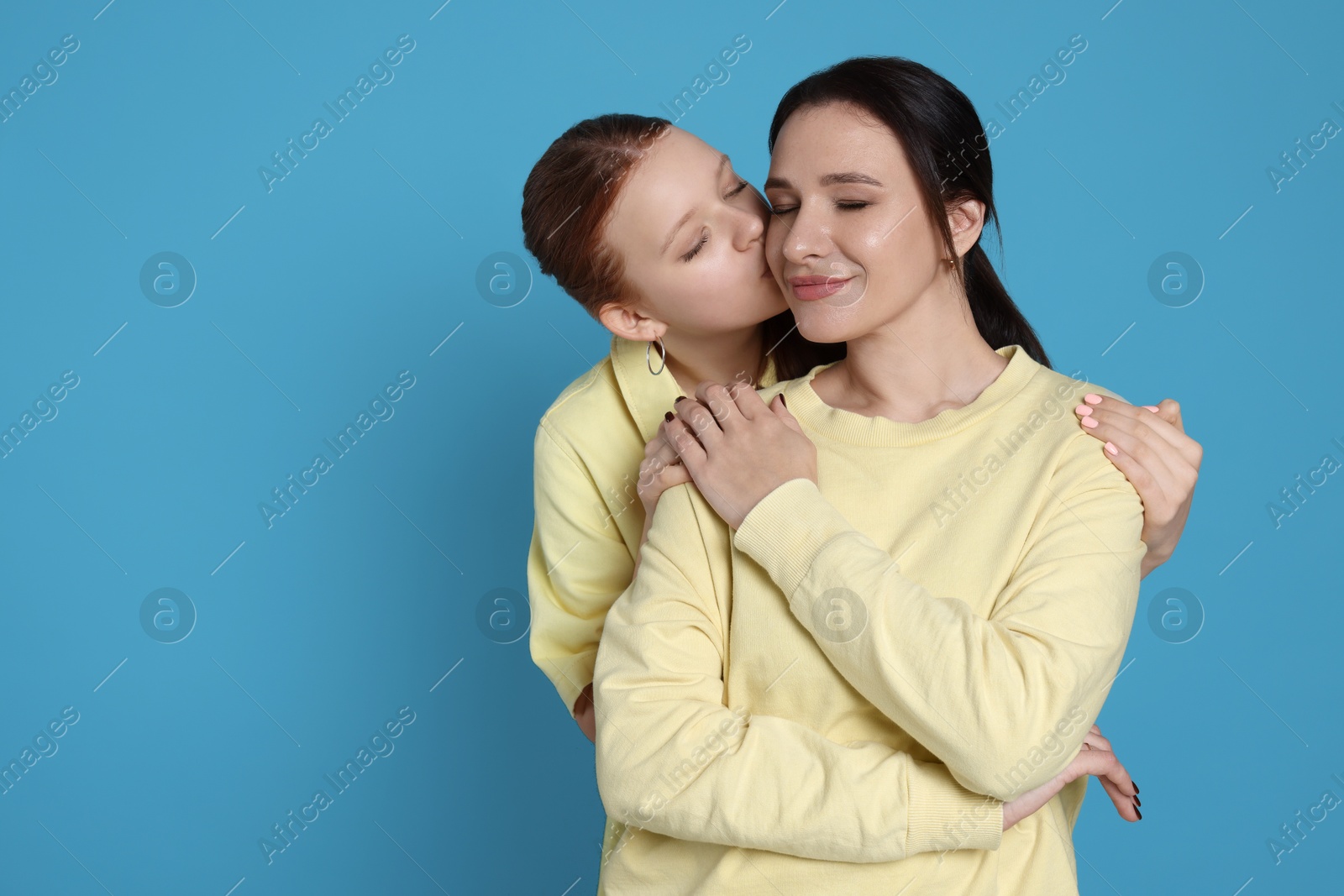 Photo of Portrait of beautiful mother with teenage daughter on light blue background, space for text