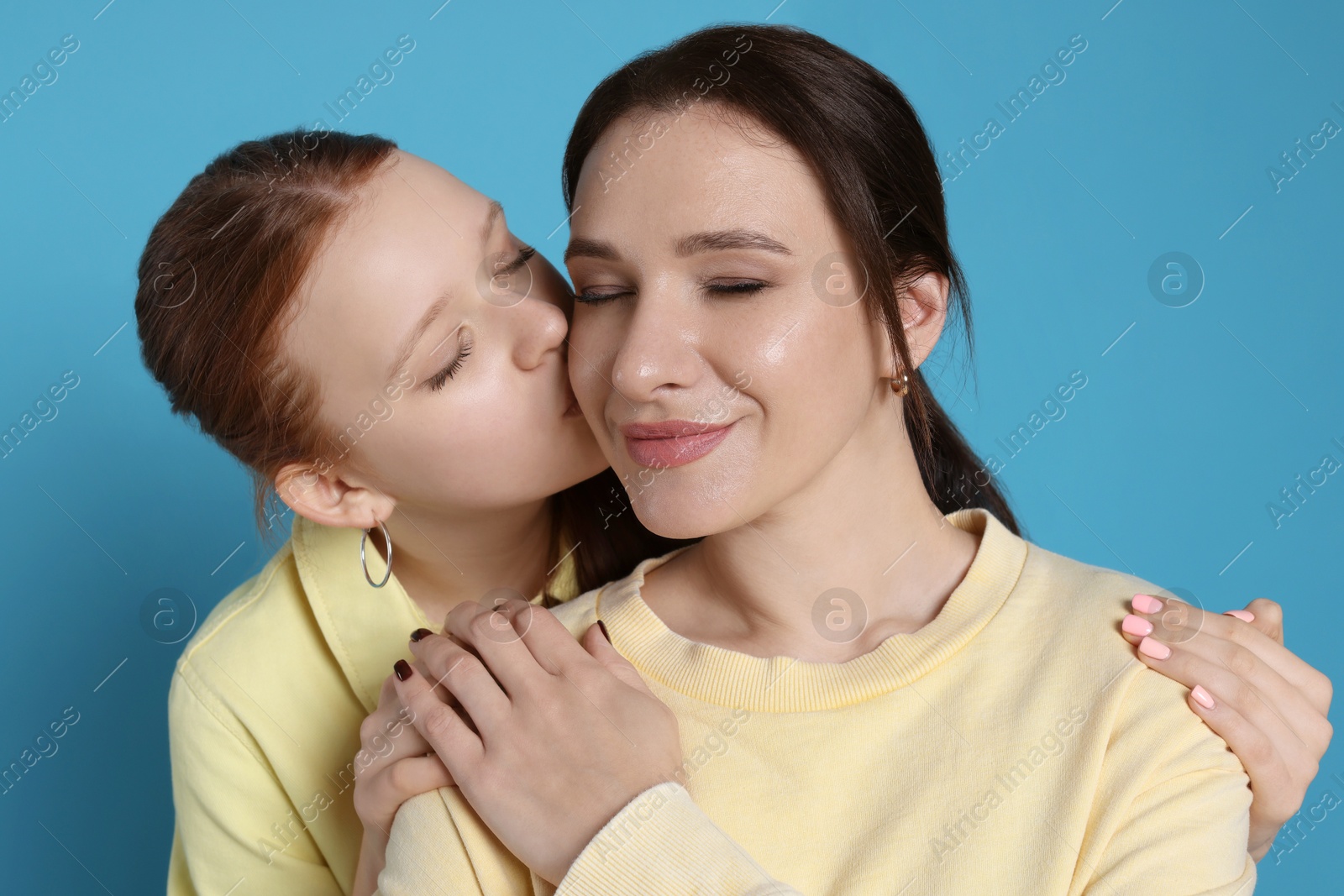 Photo of Portrait of beautiful mother with teenage daughter on light blue background