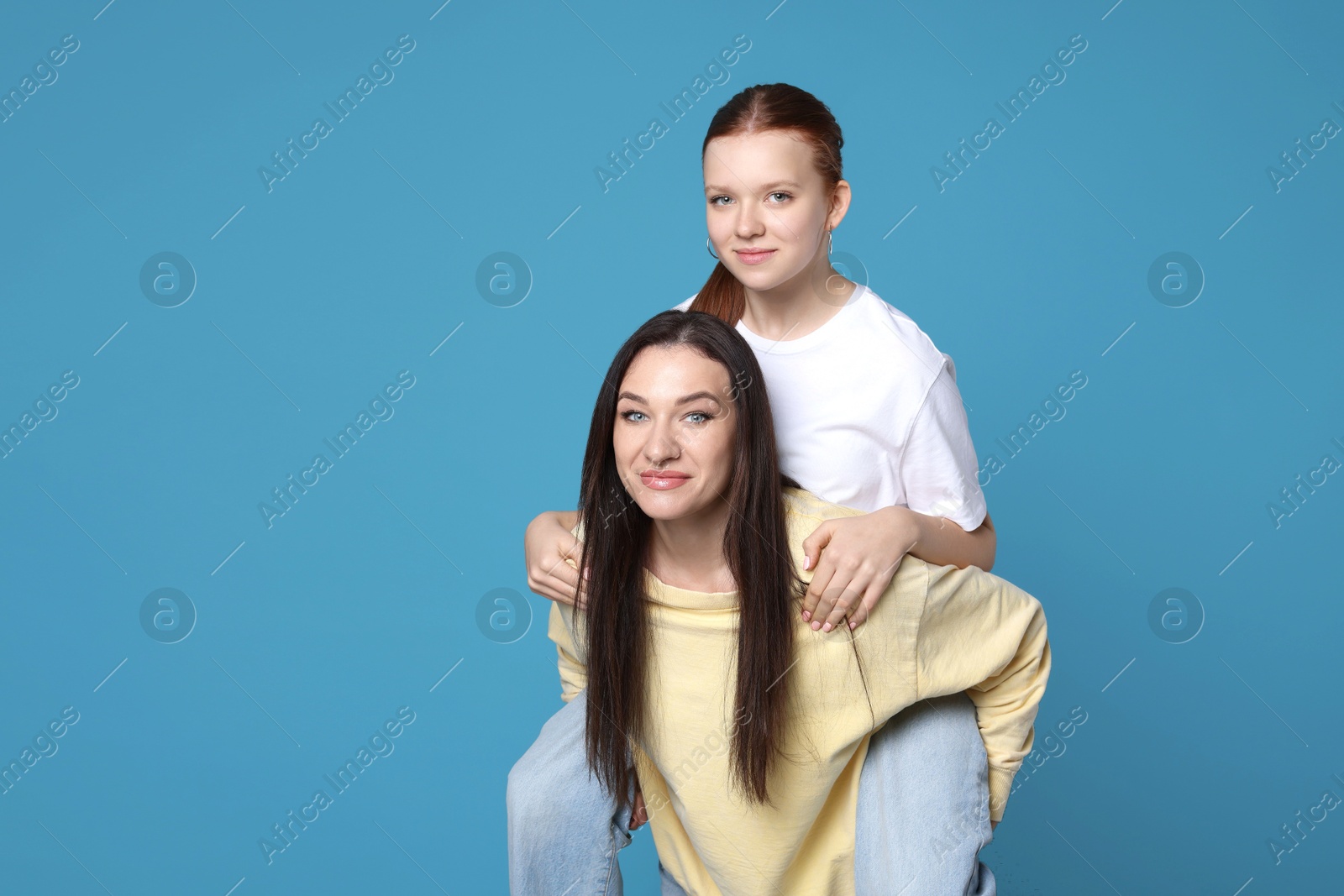 Photo of Portrait of beautiful mother with teenage daughter on light blue background, space for text