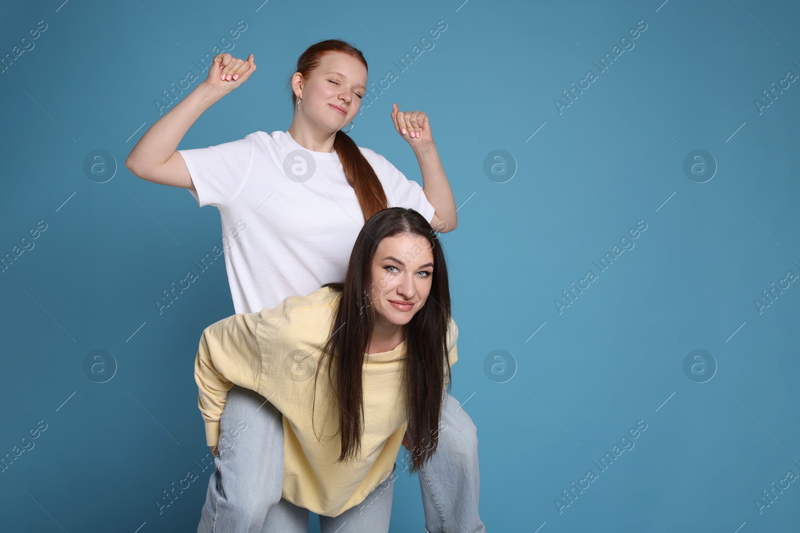 Photo of Portrait of beautiful mother with teenage daughter on light blue background, space for text