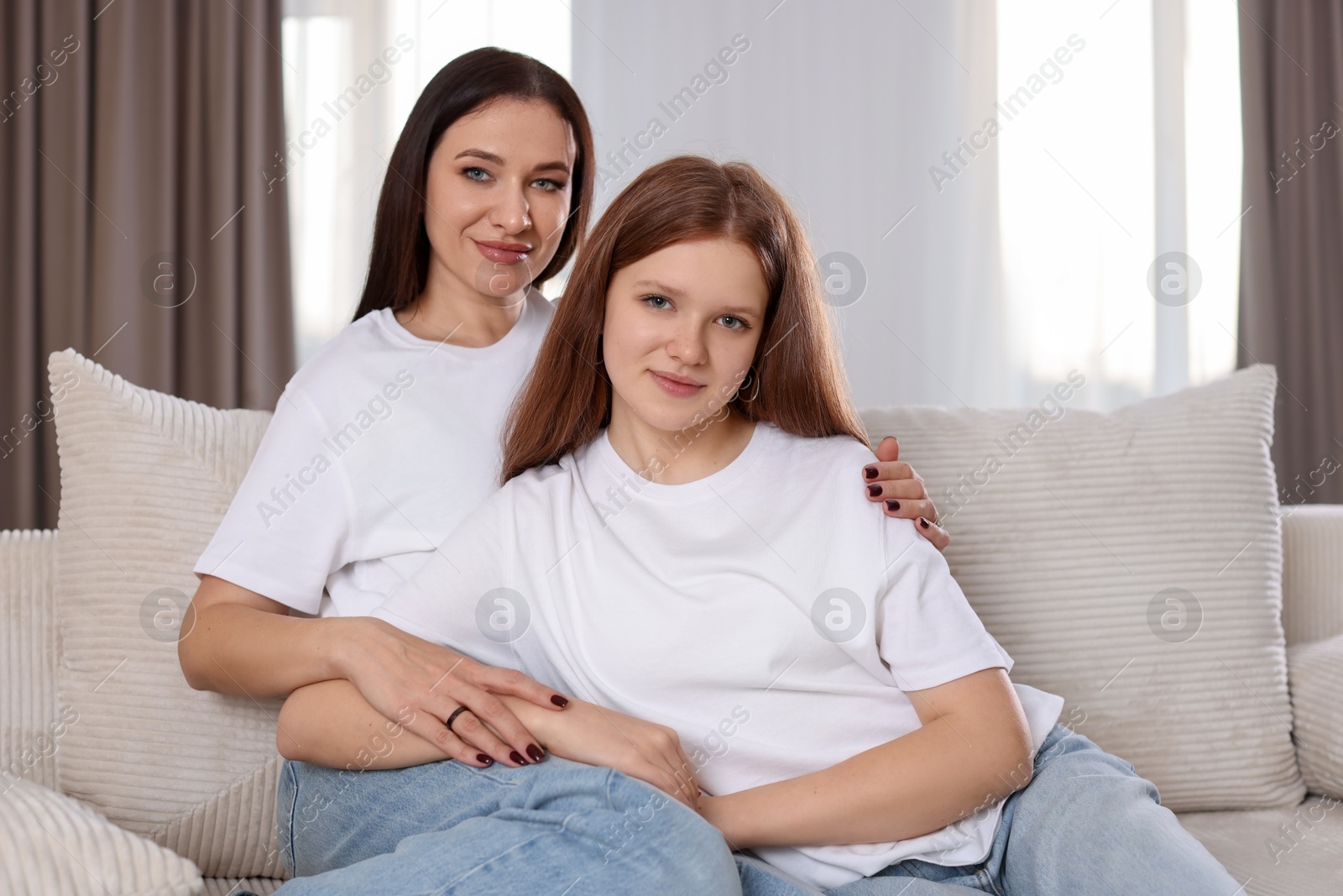 Photo of Portrait of beautiful mother with teenage daughter on sofa at home