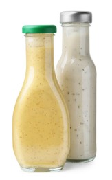 Photo of Different delicious sauces in glass bottles isolated on white