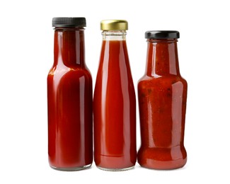 Photo of Different delicious sauces in glass bottles isolated on white