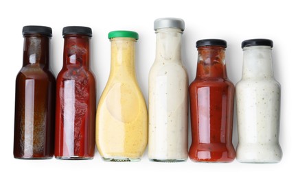 Photo of Different delicious sauces in glass bottles isolated on white, top view