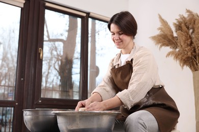 Photo of Hobby and craft. Smiling woman making pottery indoors, low angle view