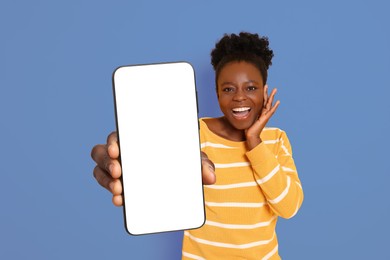 Image of Excited woman showing mobile phone with blank screen on blue background. Mockup for design