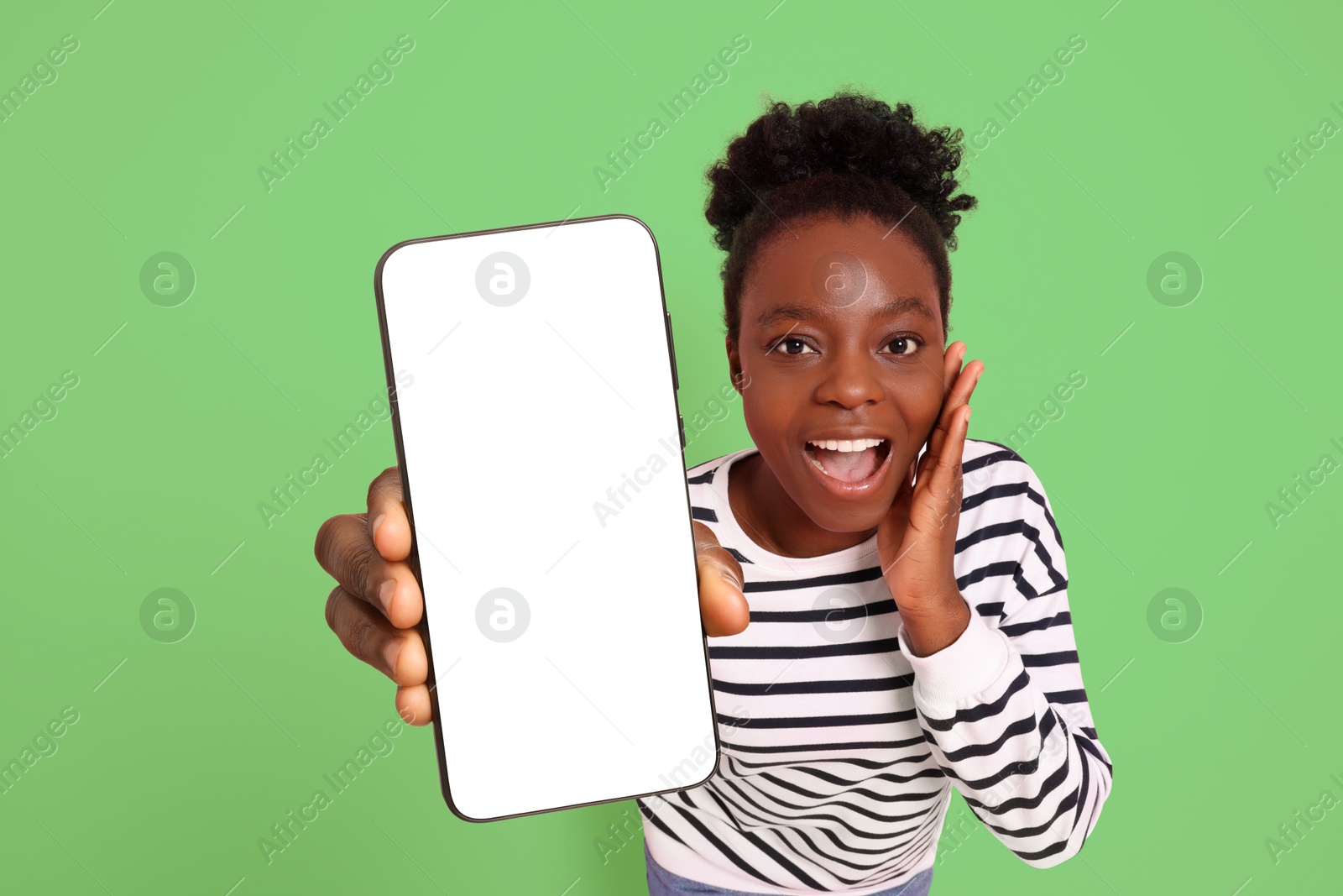 Image of Excited woman showing mobile phone with blank screen on light green background. Mockup for design