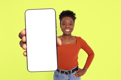 Image of Happy woman showing mobile phone with blank screen on greenish yellow background. Mockup for design