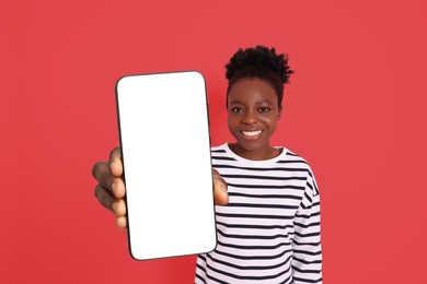 Image of Happy woman showing mobile phone with blank screen on red background. Mockup for design