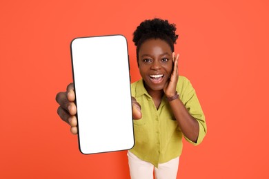 Image of Excited woman showing mobile phone with blank screen on red background. Mockup for design