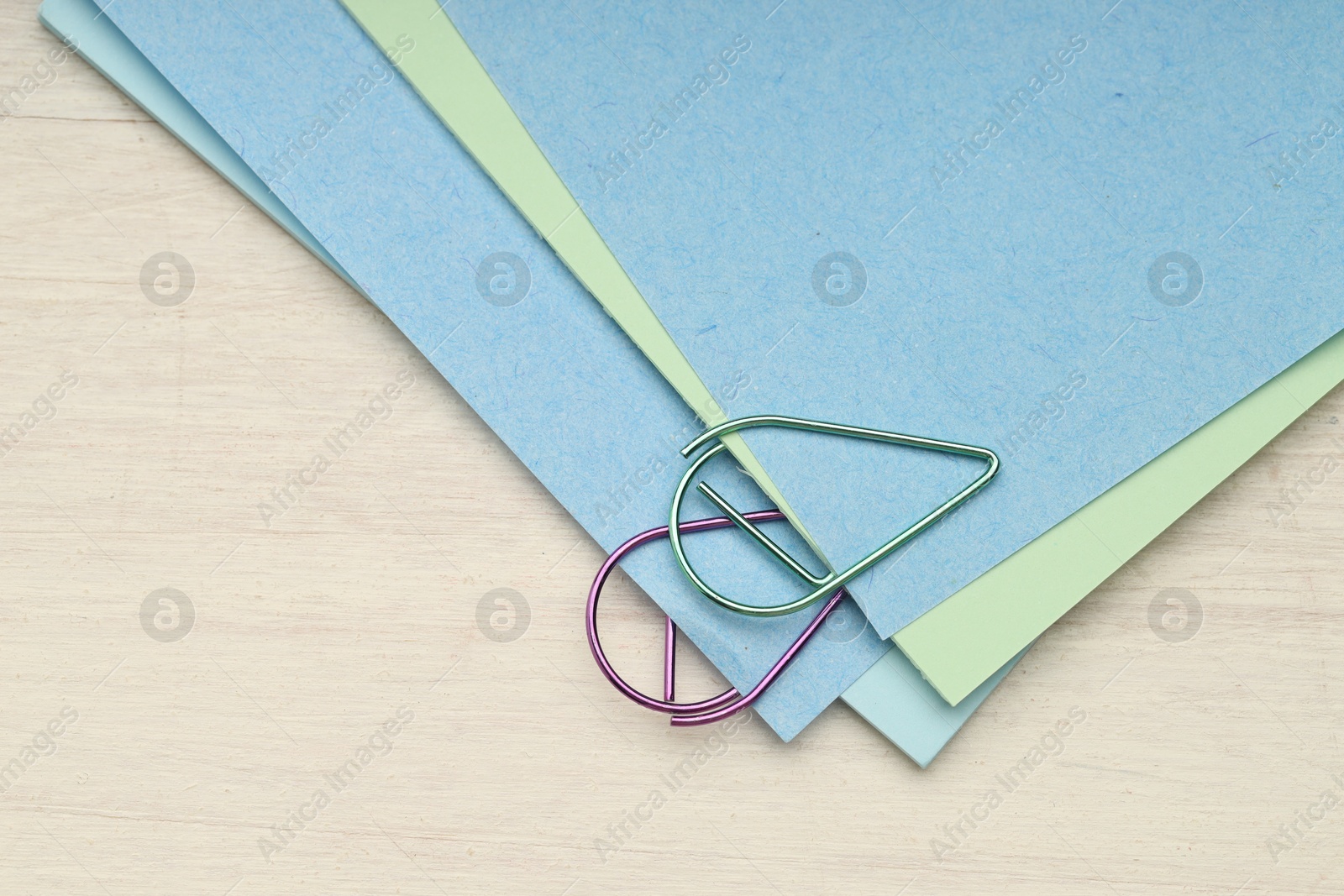 Photo of Colorful paper clips and notes on wooden table, top view. Space for text