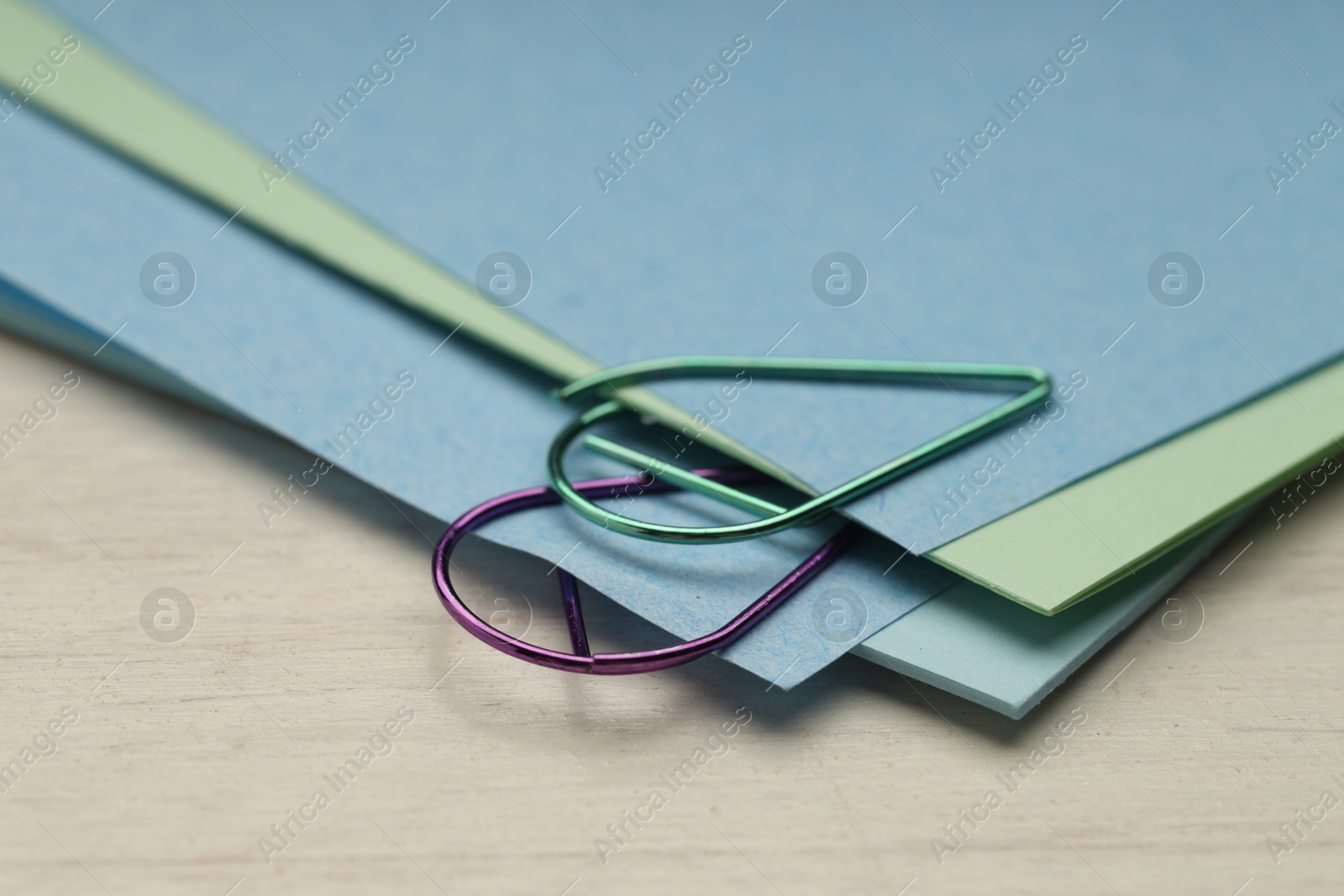 Photo of Colorful paper clips and notes on wooden table, closeup