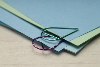 Photo of Colorful paper clips and notes on wooden table, closeup