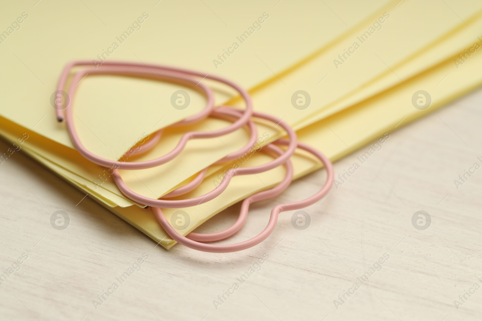 Photo of Heart shaped paper clips and notes on wooden table, closeup