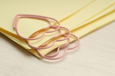 Photo of Heart shaped paper clips and notes on wooden table, closeup