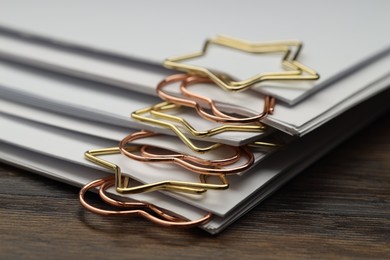 Photo of Metal paper clips and notes on wooden table, closeup