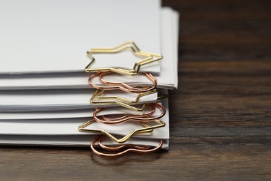 Photo of Metal paper clips and notes on wooden table, closeup. Space for text