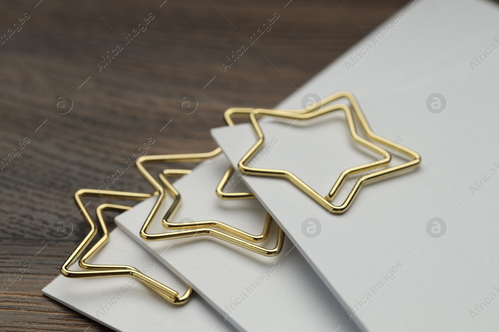 Photo of Star shaped paper clips and notes on wooden table, closeup