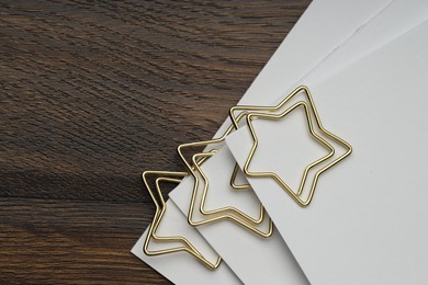 Photo of Star shaped paper clips and notes on wooden table, top view. Space for text