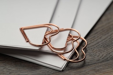 Photo of Metal paper clips and notes on wooden table, closeup