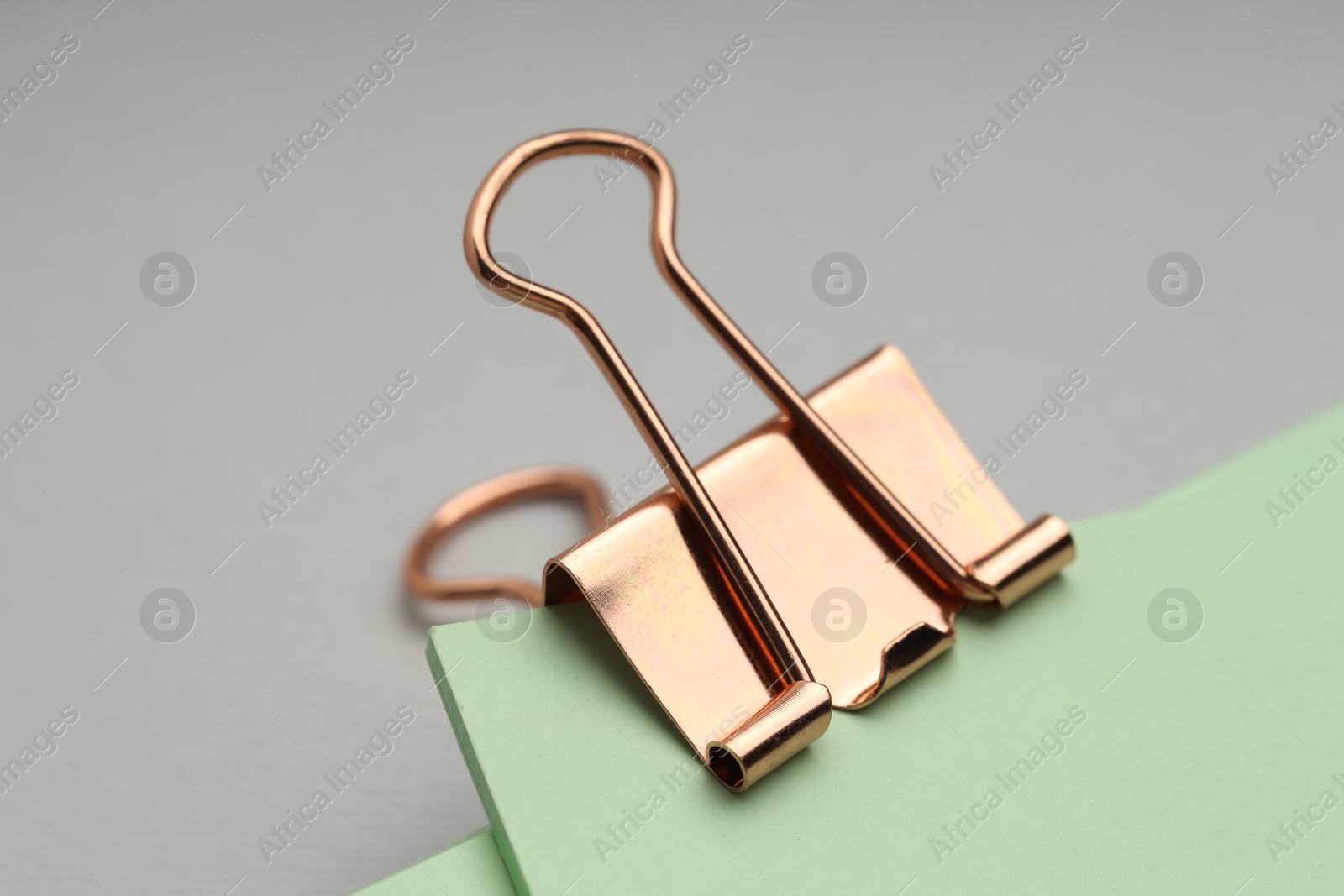 Photo of Binder clip with notes on grey background, closeup