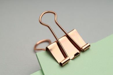 Photo of Binder clip with notes on grey background, closeup