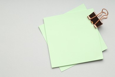 Photo of Binder clip with notes on grey background, top view. Space for text