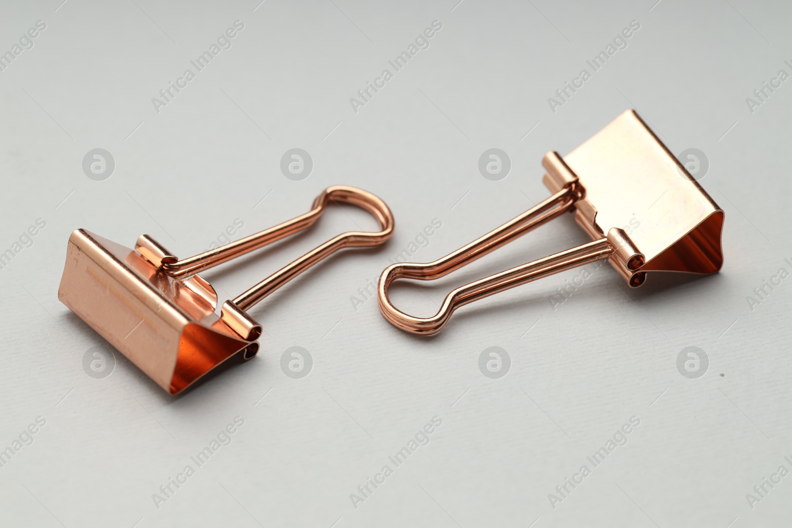 Photo of Two binder clips on grey background, closeup