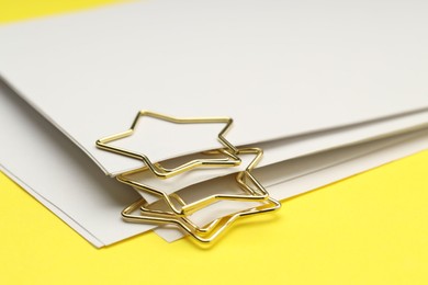 Photo of Star shaped paper clips and notes on yellow background, closeup