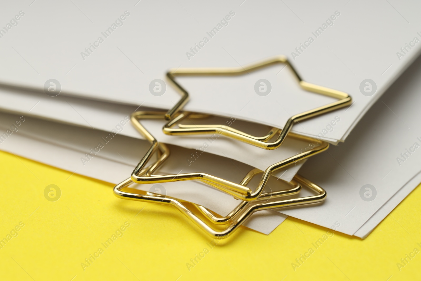 Photo of Star shaped paper clips and notes on yellow background, closeup