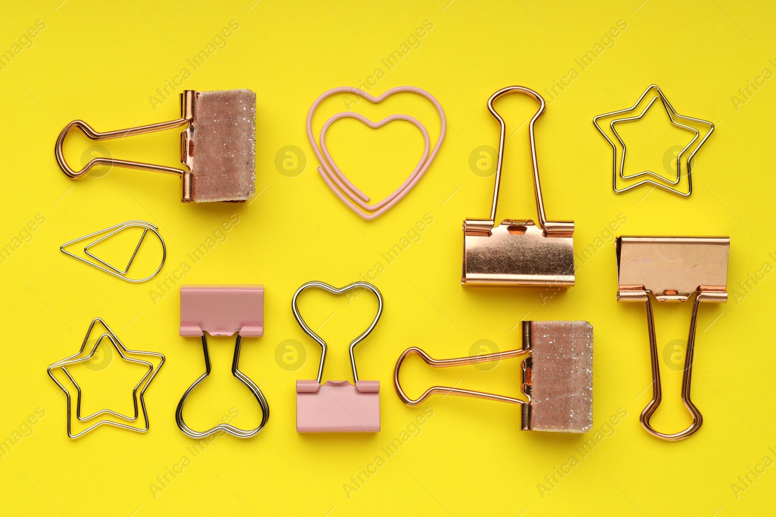 Photo of Different paper clips on yellow background, flat lay