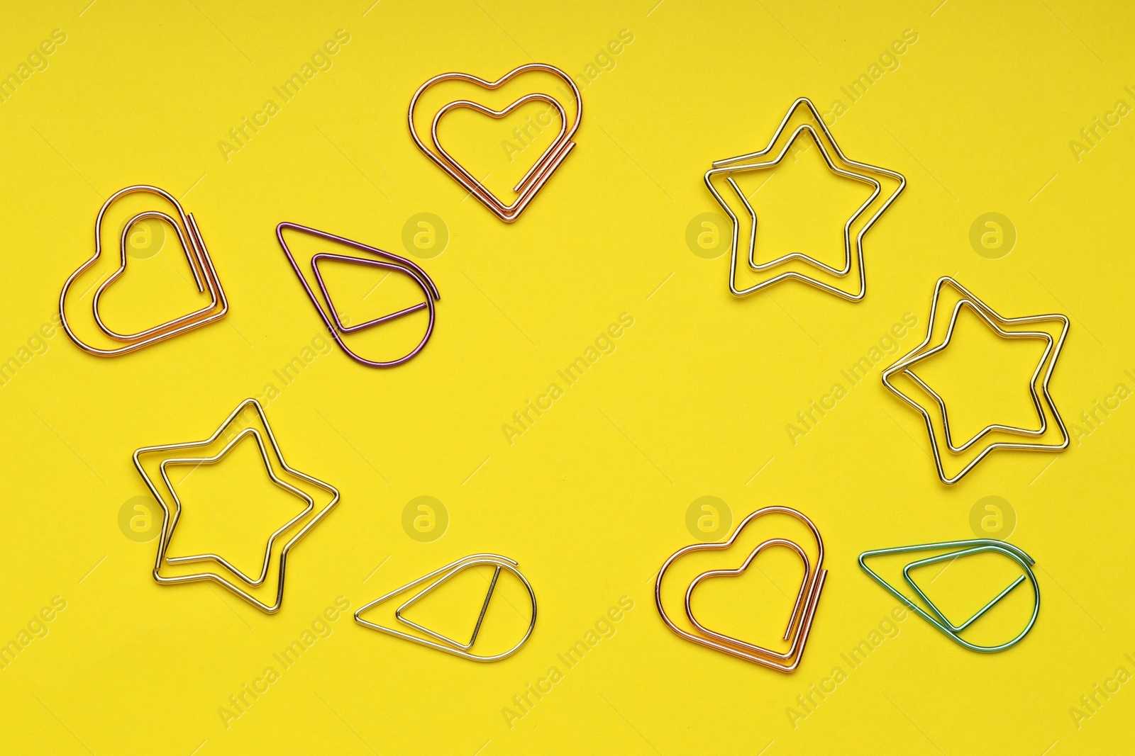 Photo of Frame of different paper clips on yellow background, flat lay. Space for text