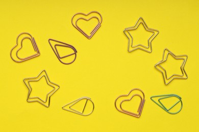 Photo of Frame of different paper clips on yellow background, flat lay. Space for text