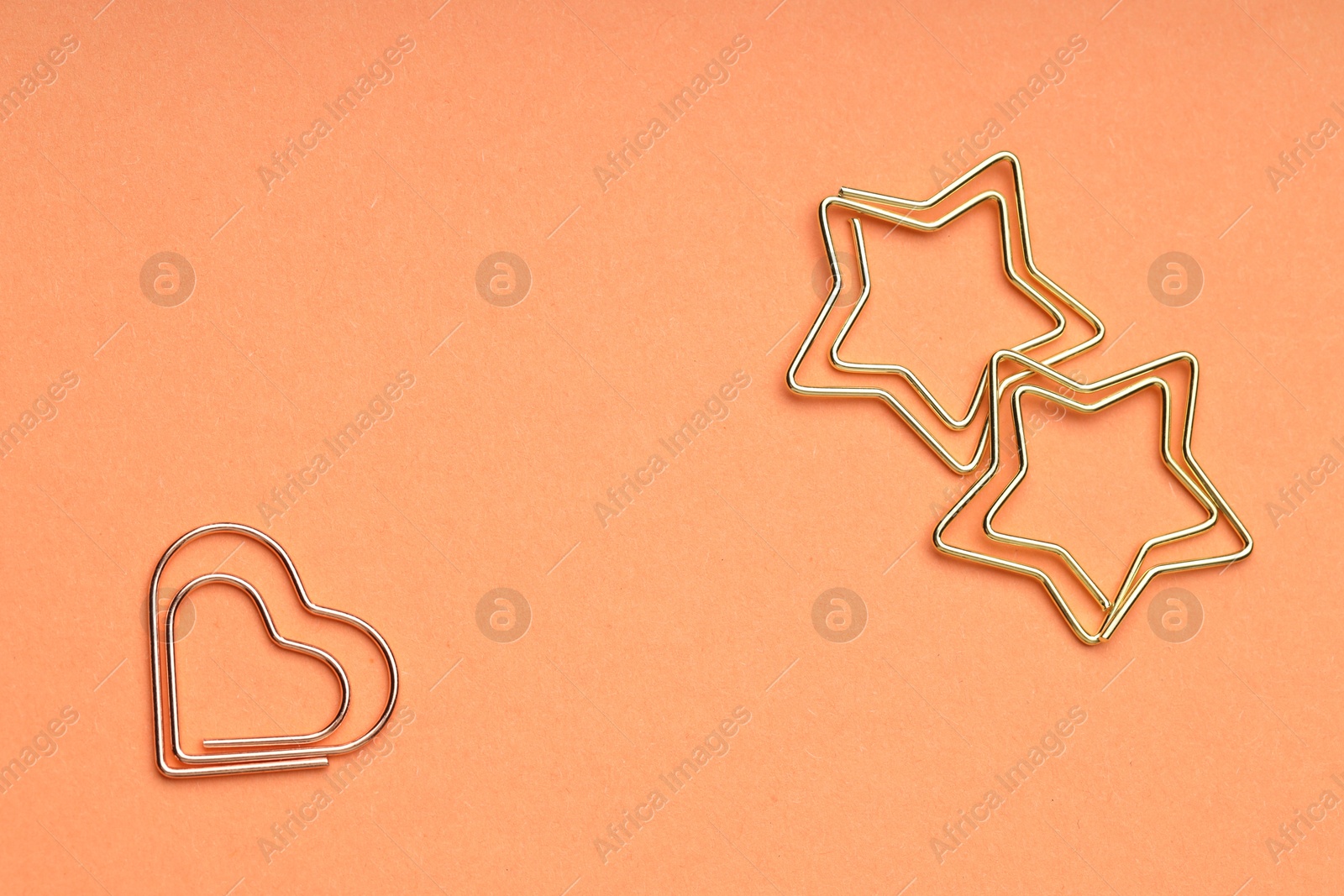 Photo of Metal paper clips on coral background, flat lay. Space for text