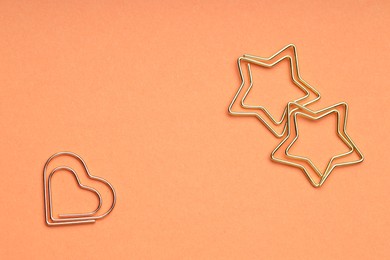 Photo of Metal paper clips on coral background, flat lay. Space for text