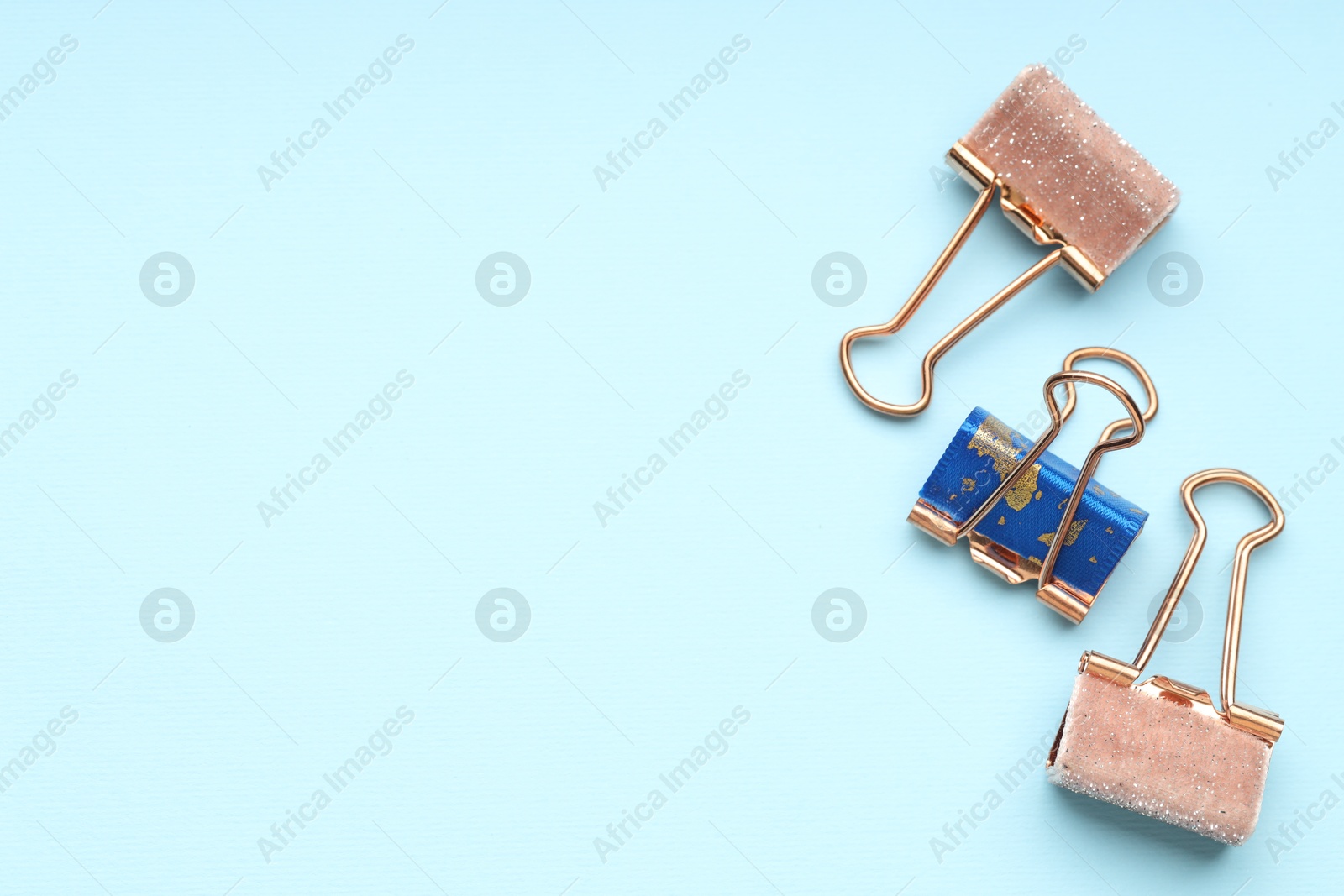 Photo of Different binder clips on light blue background, flat lay. Space for text