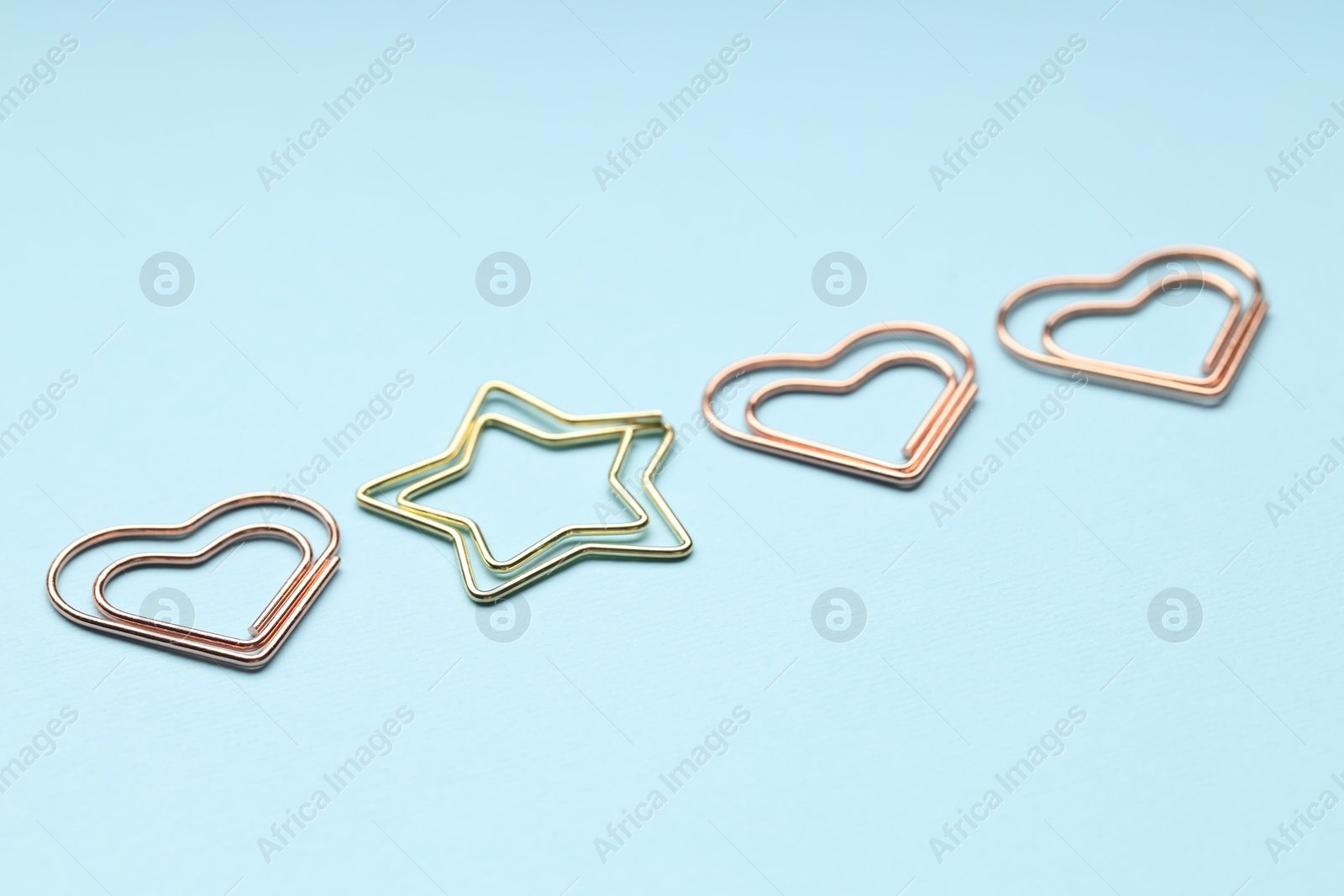 Photo of Different paper clips on light blue background, closeup