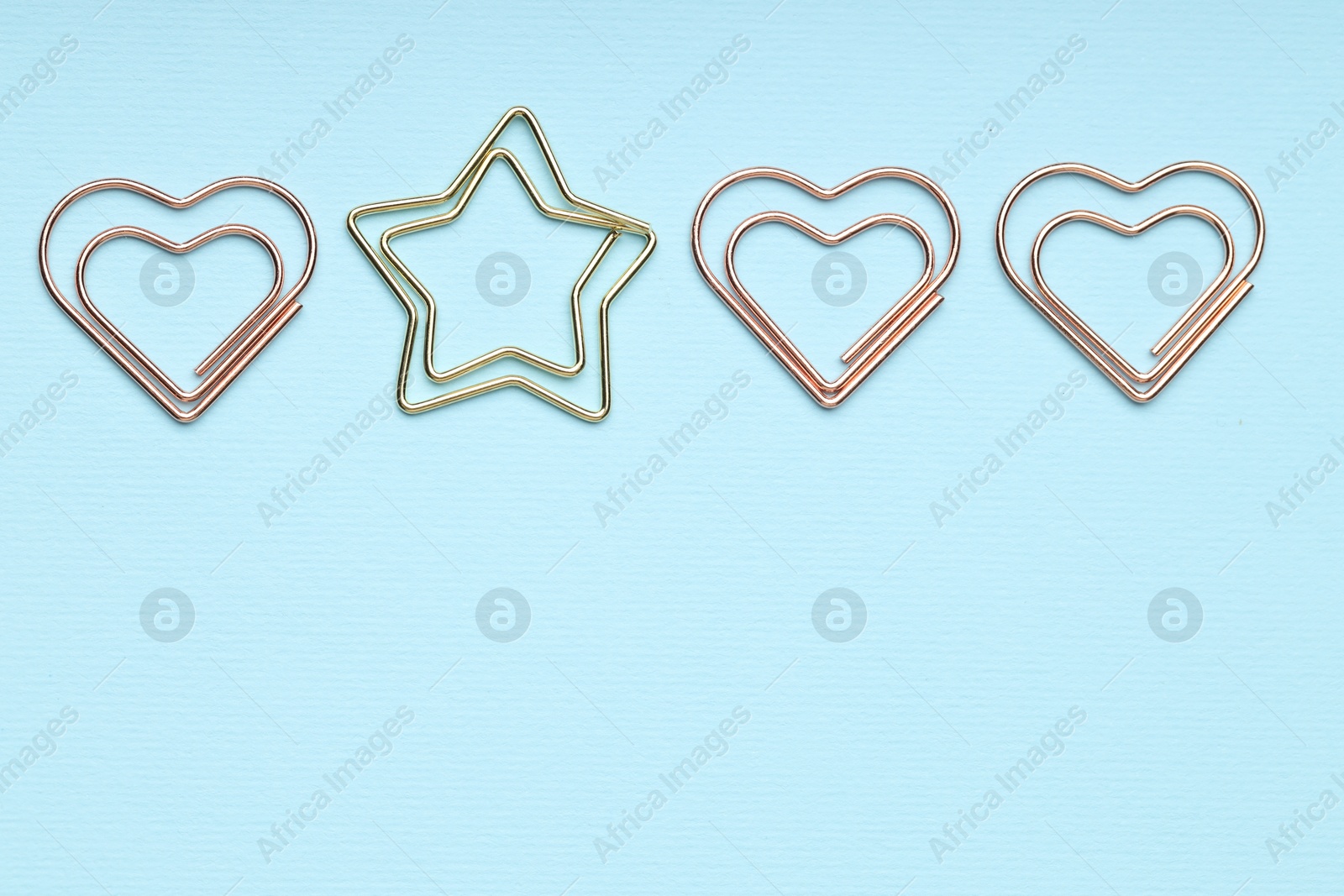 Photo of Different paper clips on light blue background, flat lay. Space for text