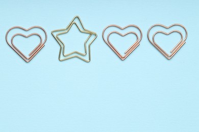 Photo of Different paper clips on light blue background, flat lay. Space for text