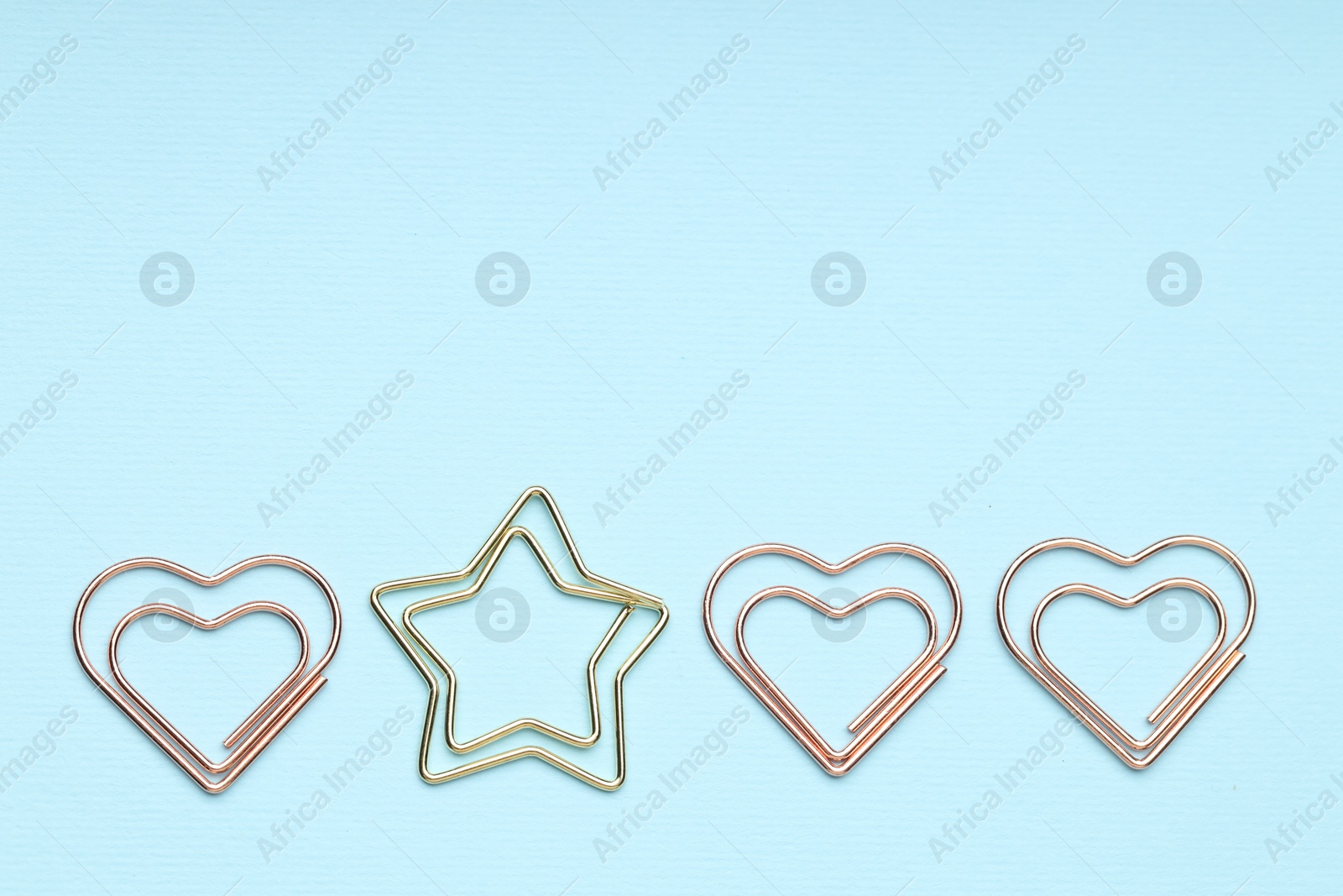 Photo of Different paper clips on light blue background, flat lay. Space for text