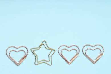 Photo of Different paper clips on light blue background, flat lay. Space for text