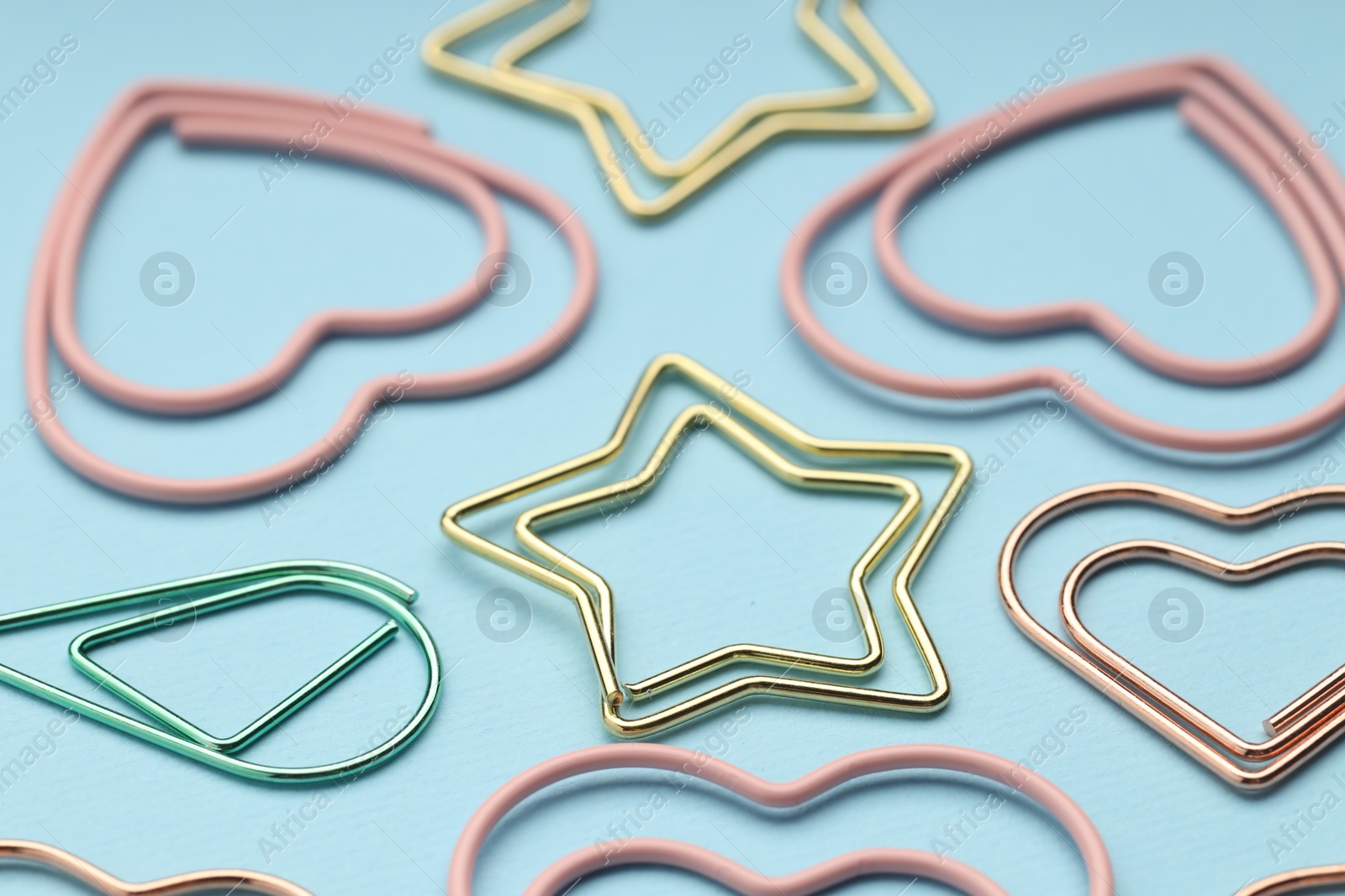 Photo of Different paper clips on light blue background, closeup