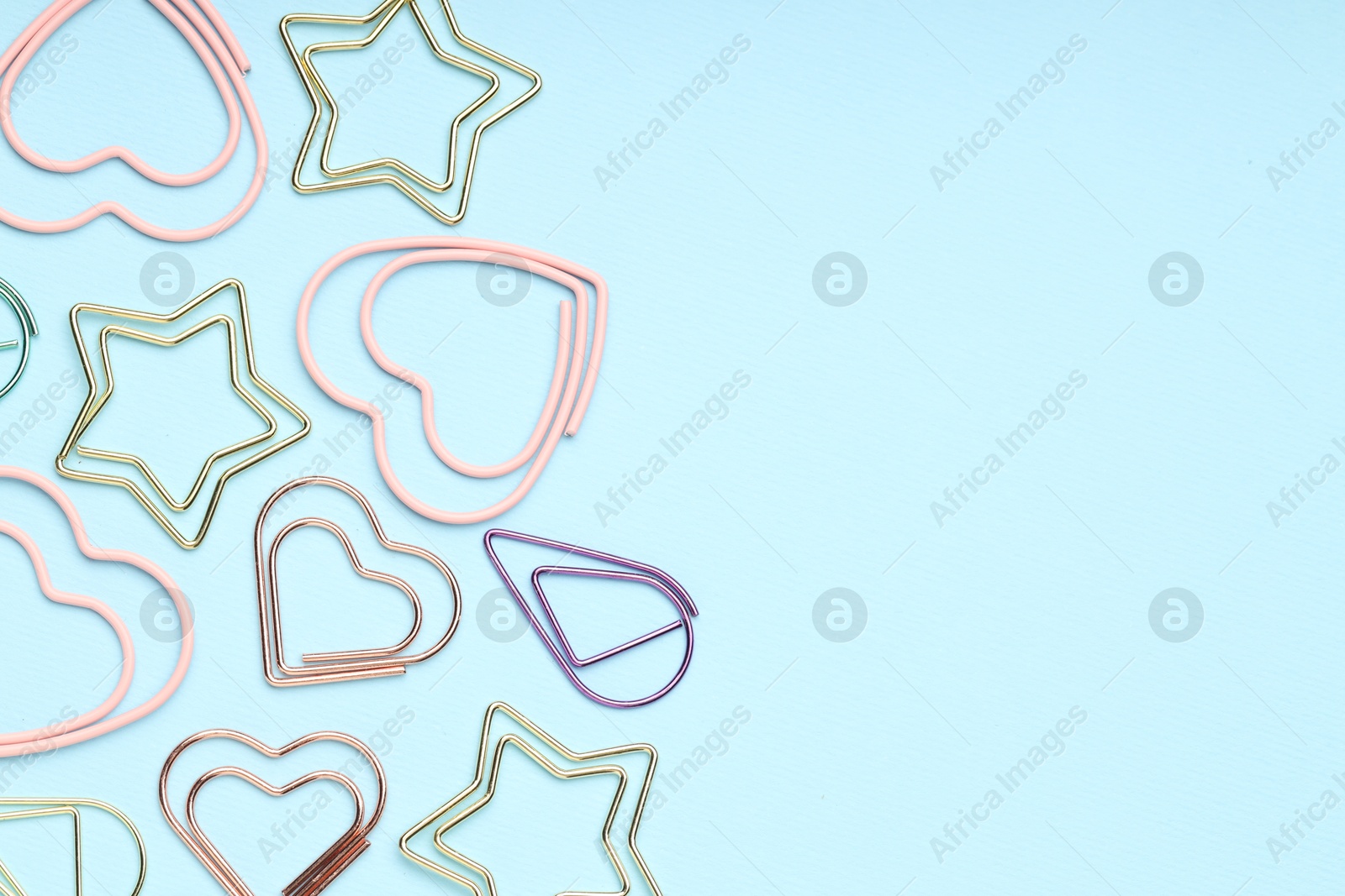 Photo of Different paper clips on light blue background, flat lay. Space for text