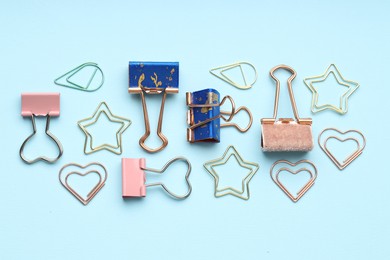 Photo of Different paper and binder clips on light blue background, flat lay