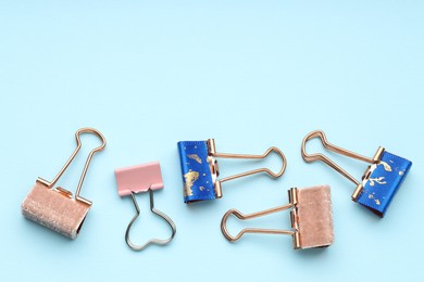 Photo of Different binder clips on light blue background, flat lay. Space for text