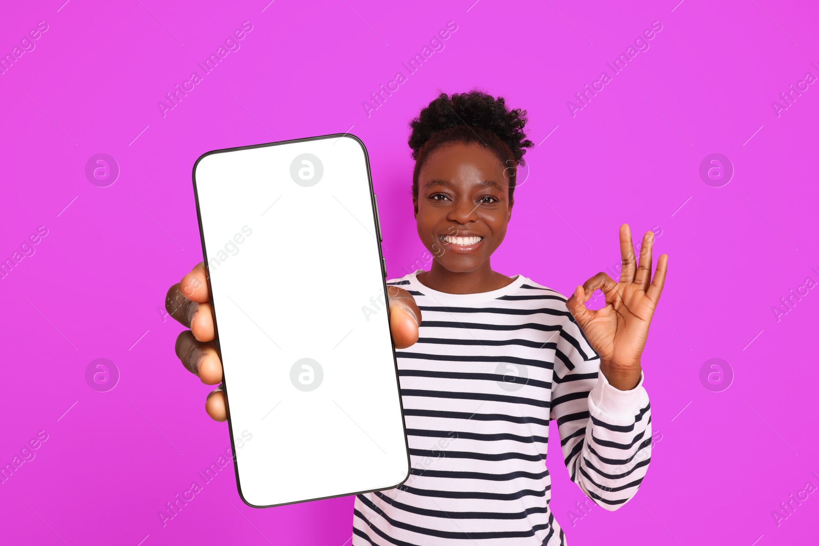 Image of Happy woman showing mobile phone with blank screen and gesture ok on magenta color background. Mockup for design