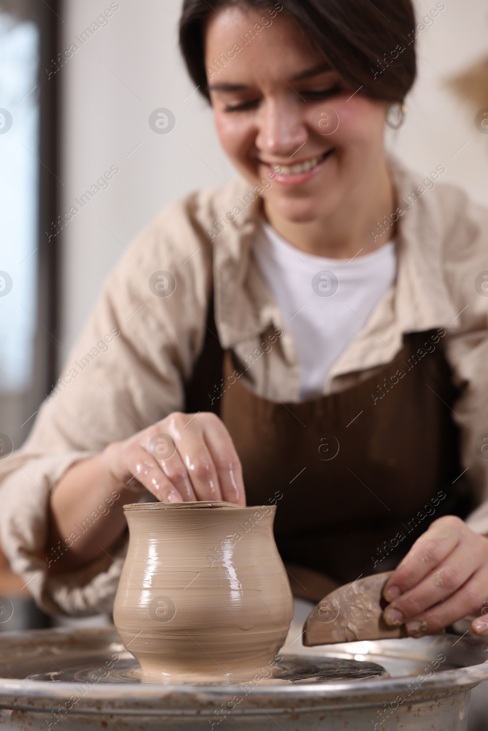 Photo of Hobby and craft. Smiling woman making pottery indoors, selective focus